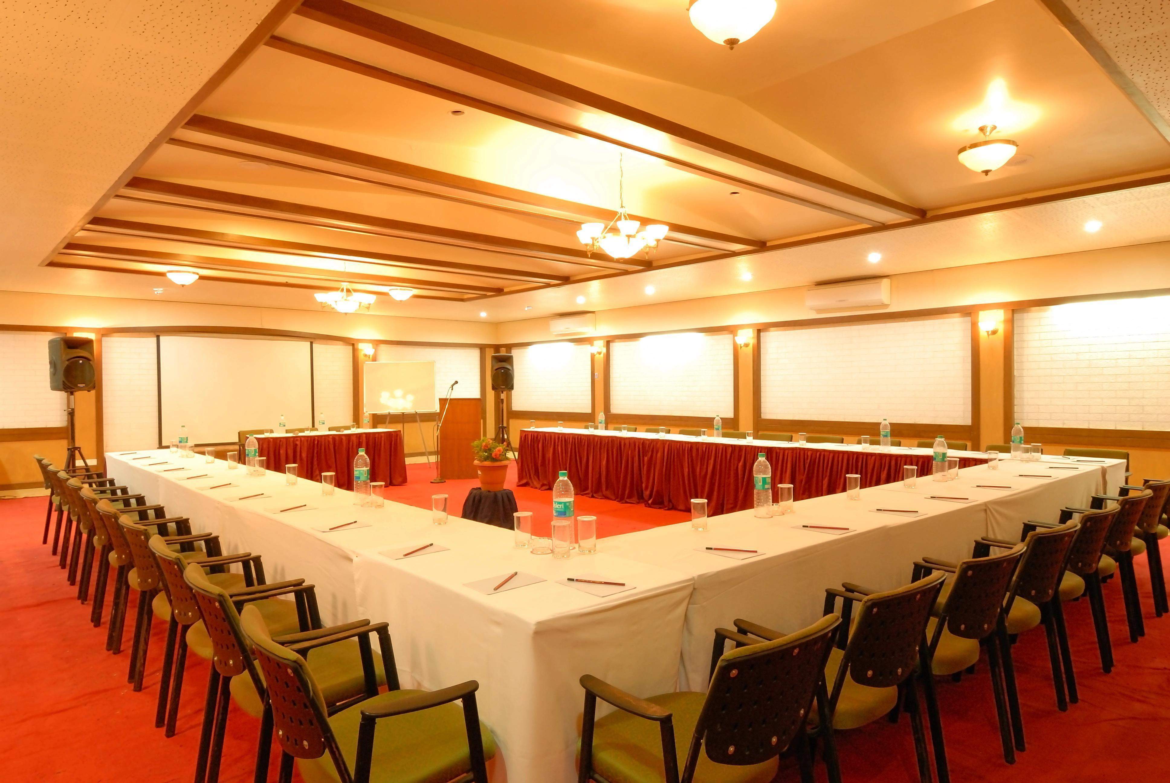 A spacious conference room at Ramsukh Resort with a U-shaped table arrangement, comfortable seating, and a projector setup for business meetings.